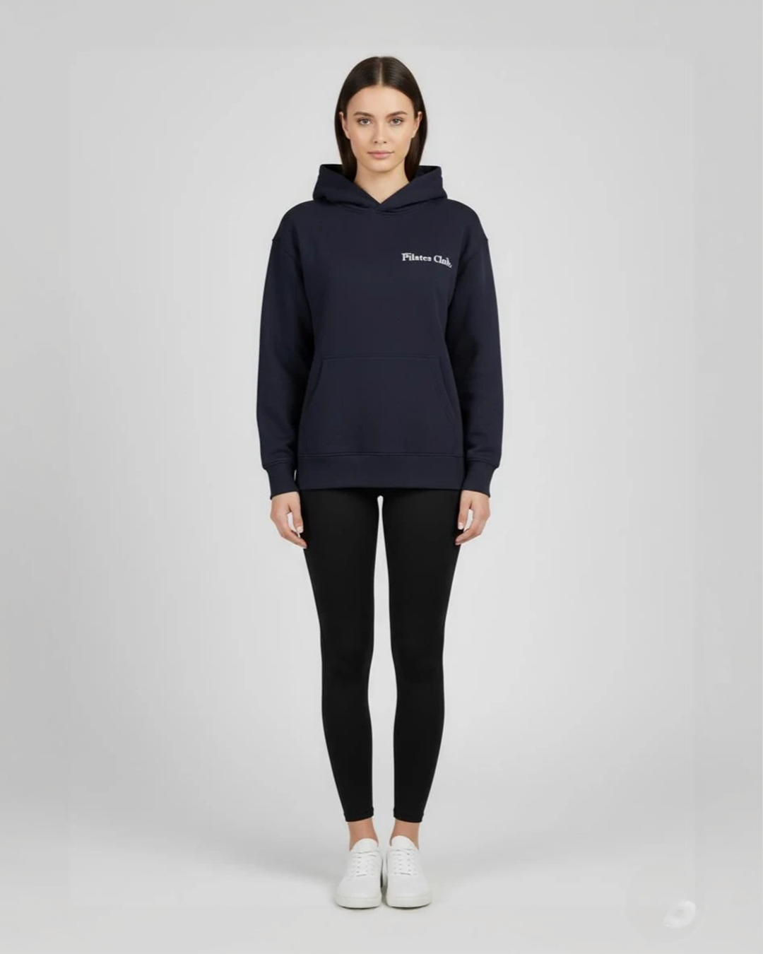 Person wearing a navy hoodie and black leggings on a white background