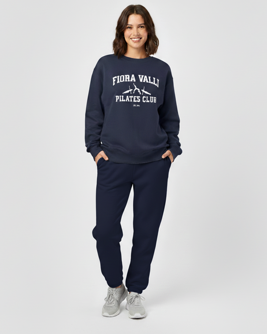 Person wearing navy 'Flora Vally Pilates Club' sweatshirt and pants on a white background