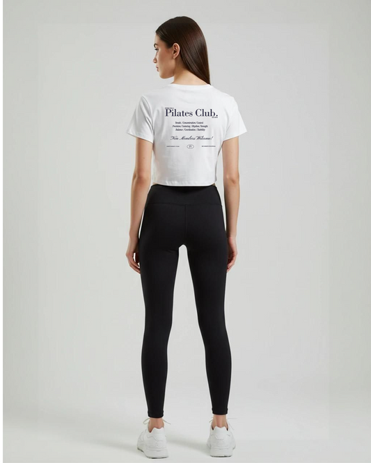 Person wearing a white 'Pilates Club' t-shirt and black leggings on a plain background