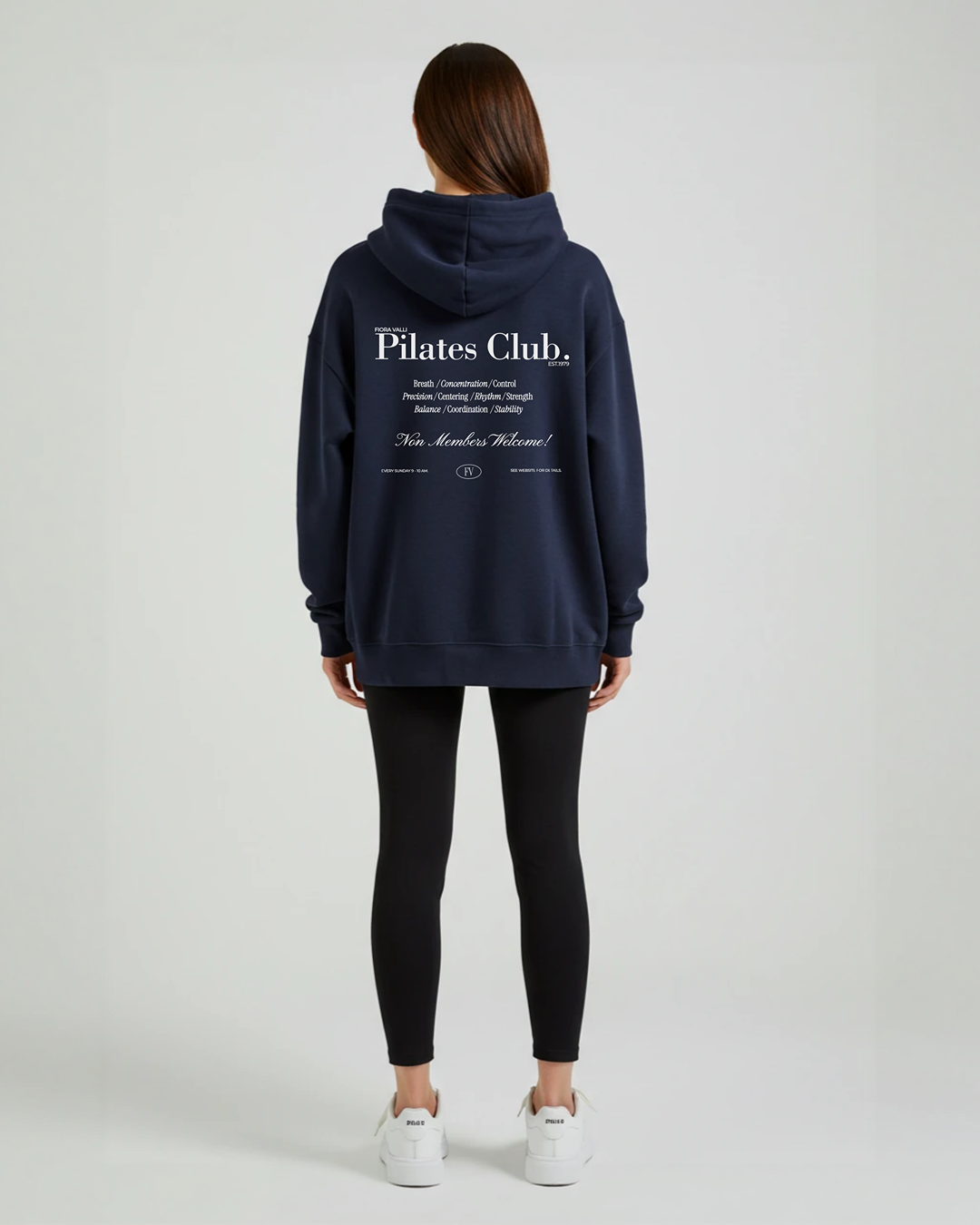 Person wearing a navy hoodie with 'Pilates Club' text on the back, standing against a white background.