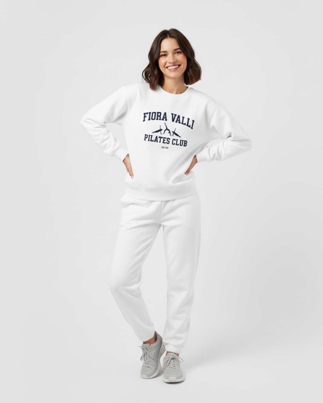 Woman wearing a white sweatshirt with text and pants on a plain background