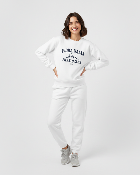 Woman wearing a white sweatshirt with text and pants on a plain background