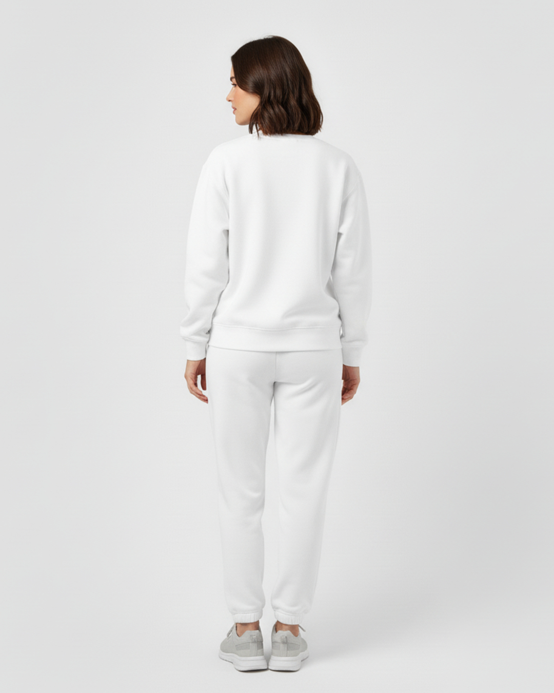 Person wearing a white sweatshirt and pants on a light gray background