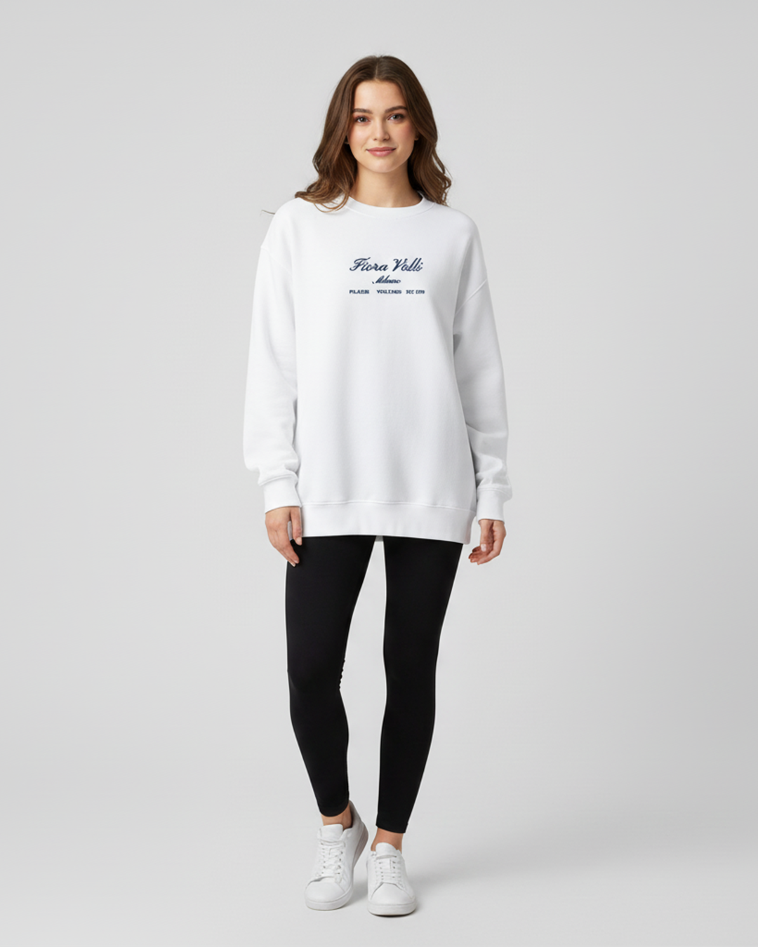 Woman wearing a white sweatshirt with text and black leggings on a light gray background