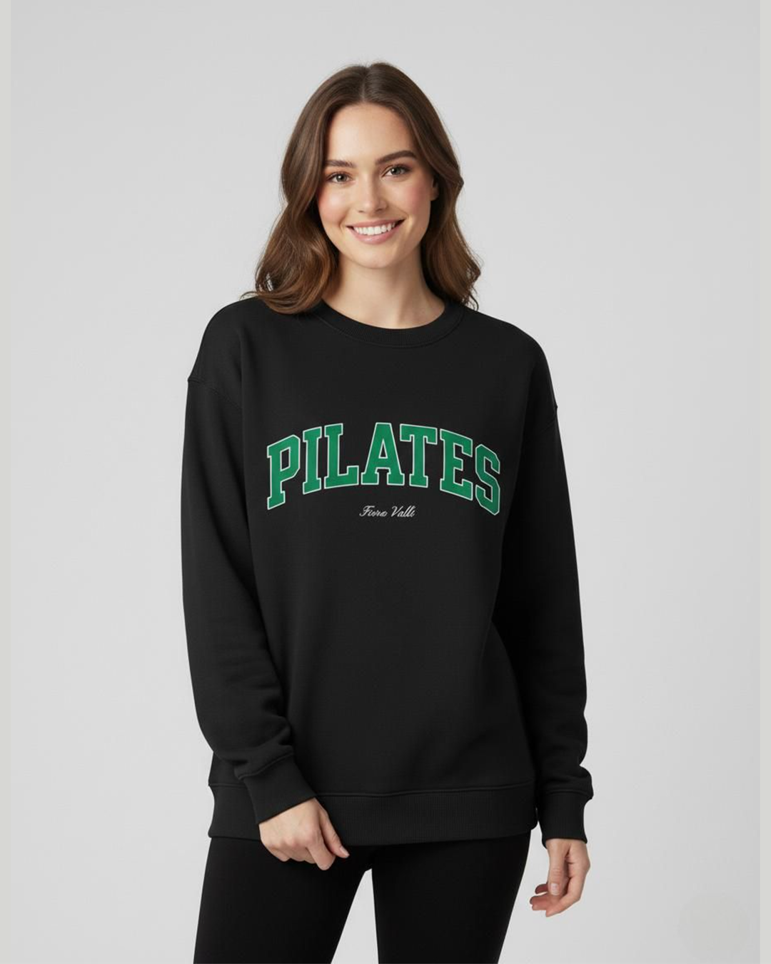 Woman wearing a black sweatshirt with 'PILATES' text on a plain background