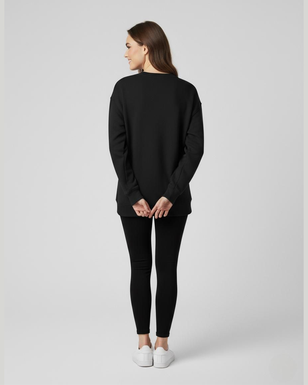 Person wearing a black long-sleeve top and black leggings on a light gray background