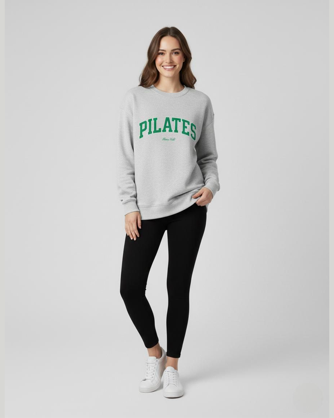 Woman wearing a gray sweatshirt with 'PILATES' text on a white background